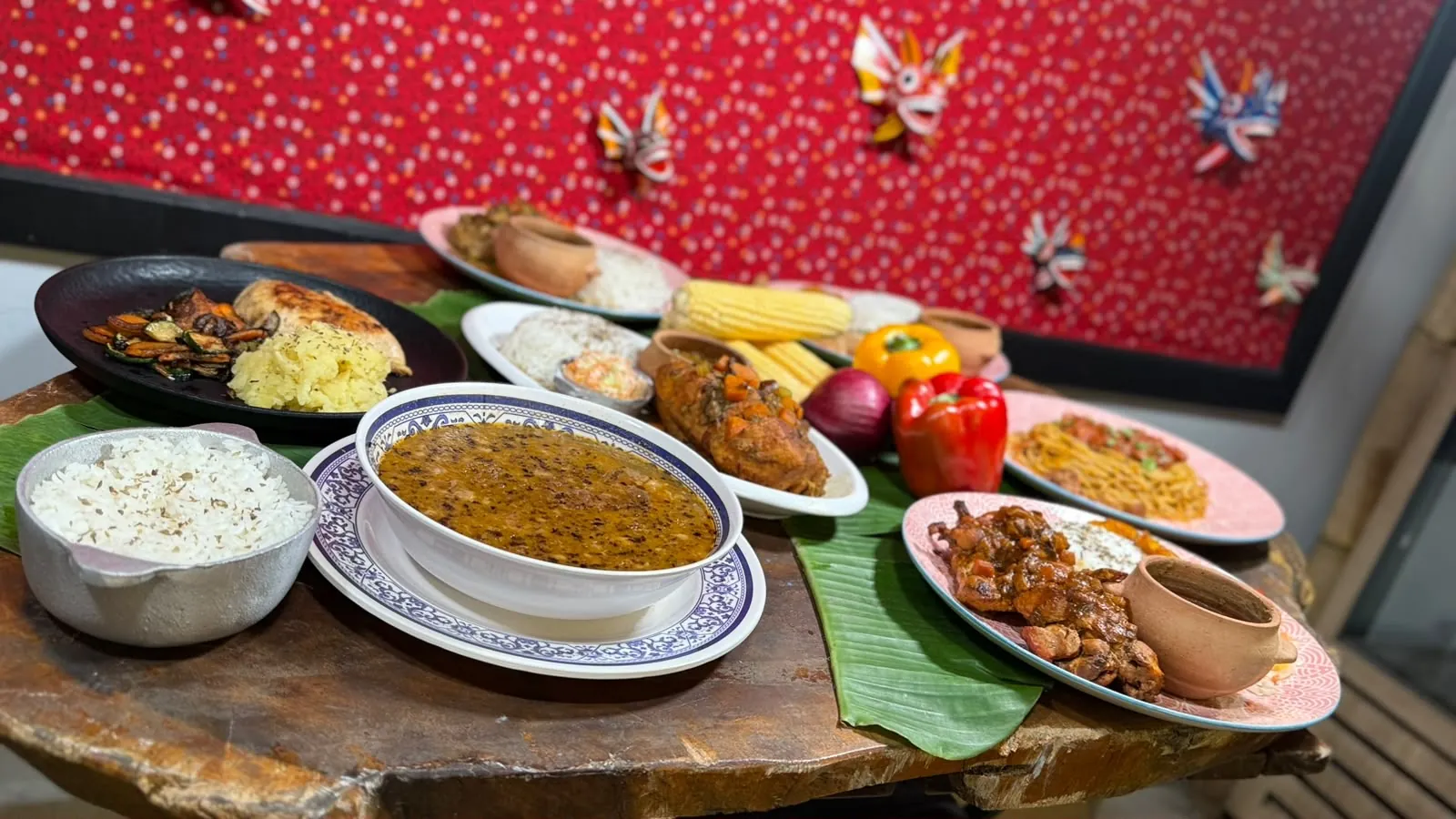 Mesa servida con platos típicos panameños: pollo guisado, sopa, espagueti y pescado frito sobre hojas de plátano