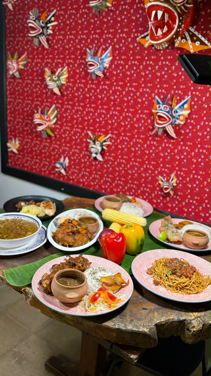 Mesa con platos panameños y arte tradicional de diablicos en la pared