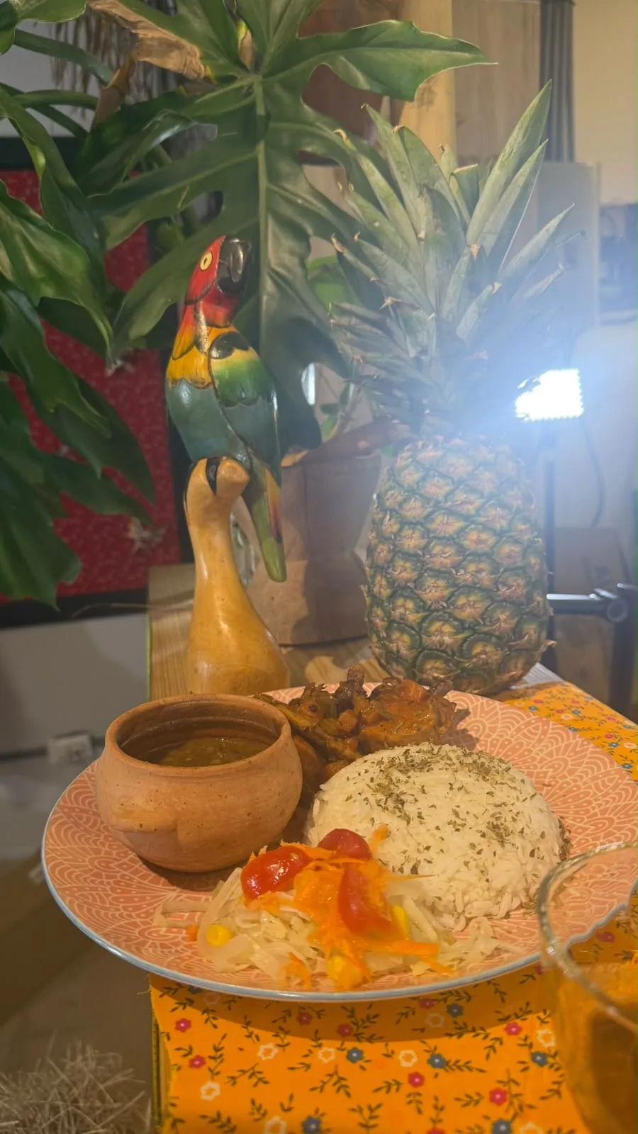Plato panameño servido junto a piña y decoración de guacamaya tallada en madera